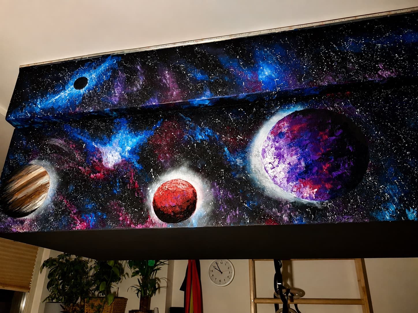A homemade climbing training board painted with a space and planets scene