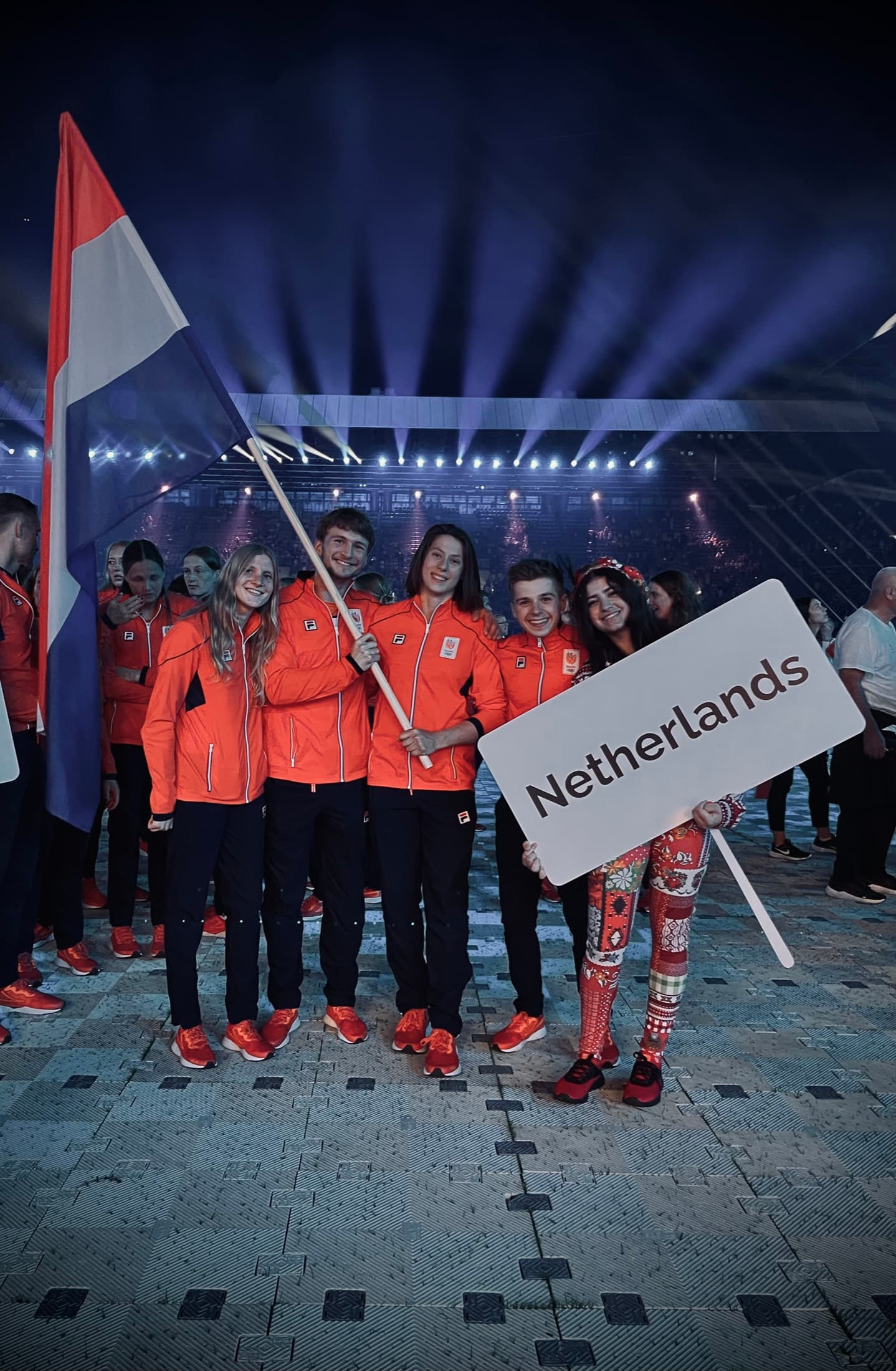 Team NL athletes in orange at the European Games opening ceremony, holding a Netherlands sign and the Dutch flag