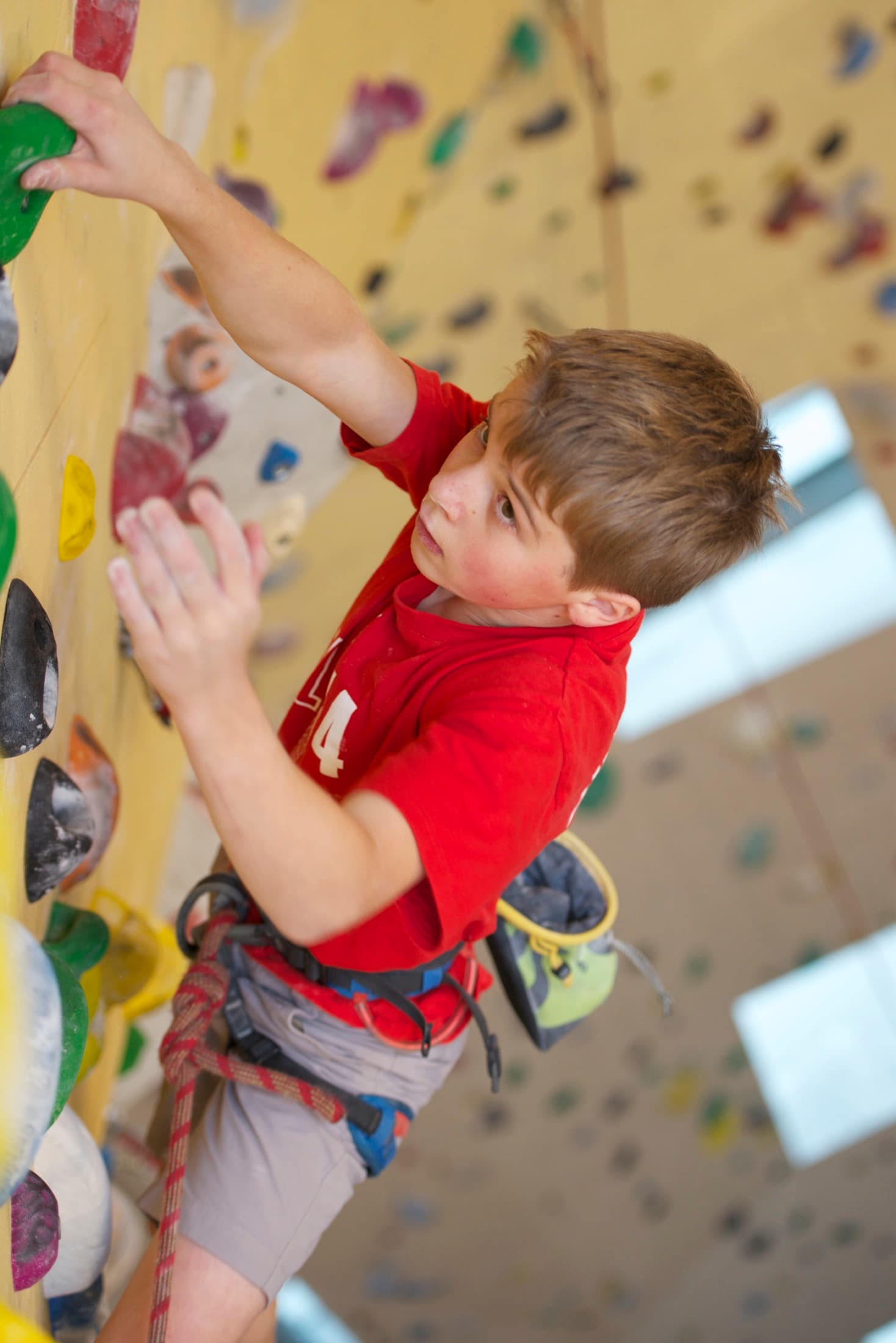 Young Leto reaching for a hold on a yellow climbing wall