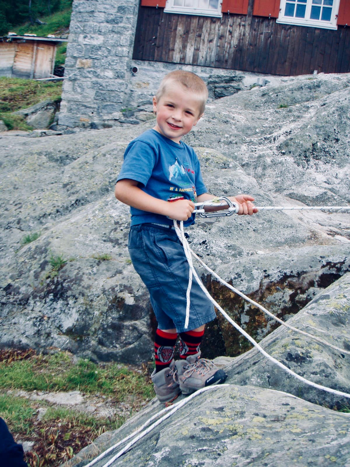 A young Leto holding a climbing rope on a rocky outcrop