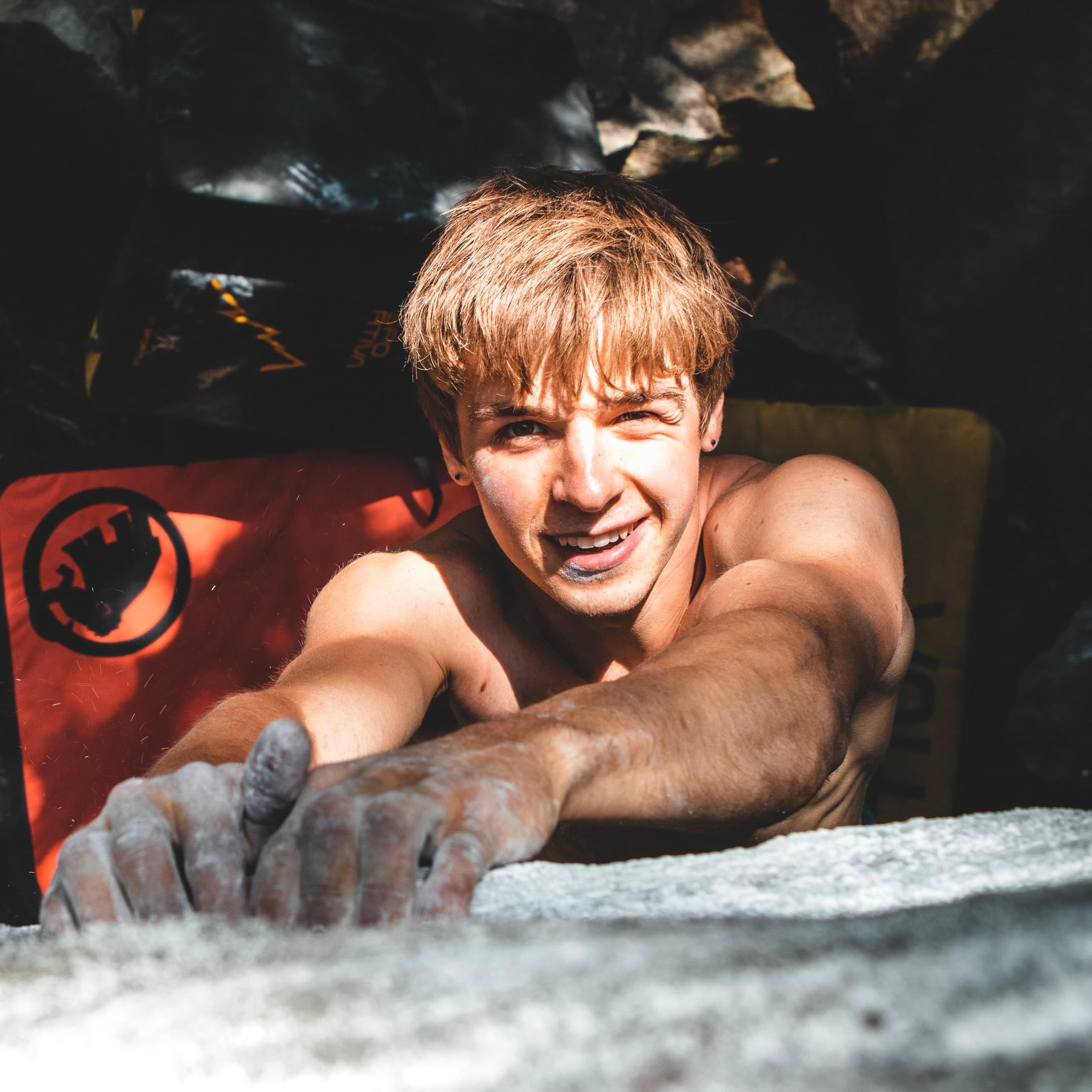 Close-up portrait with chalked hands, mid-boulder problem
