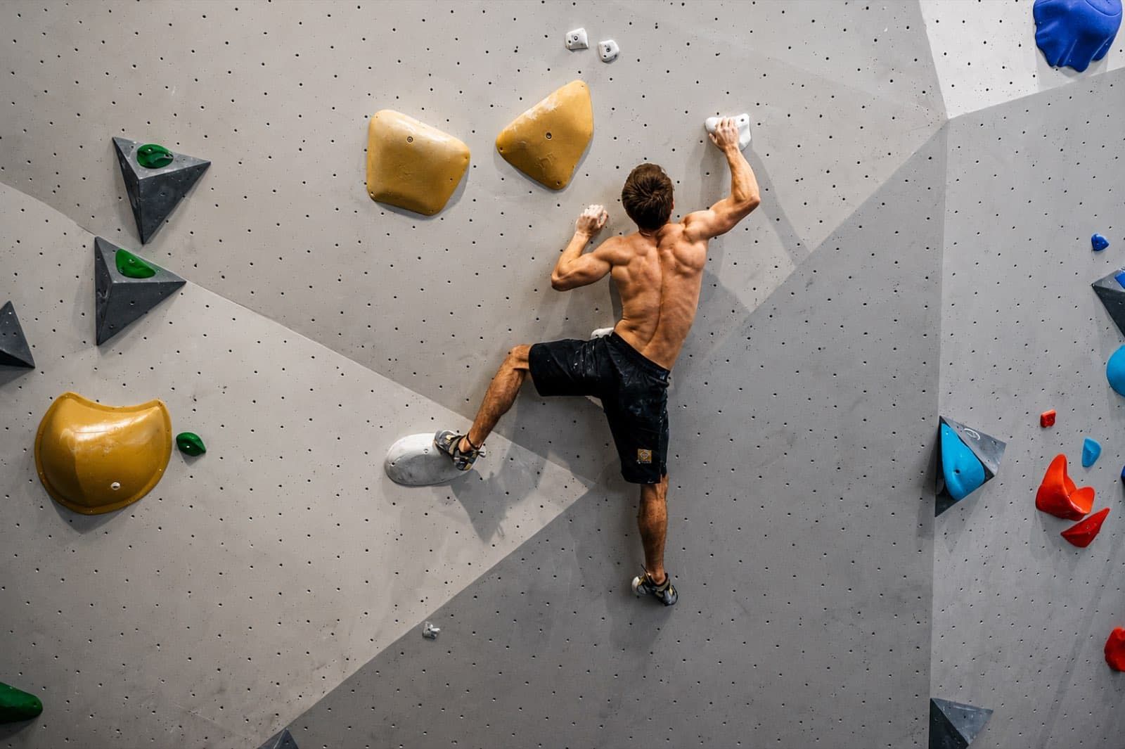 Bouldering a grey indoor wall with yellow and white holds