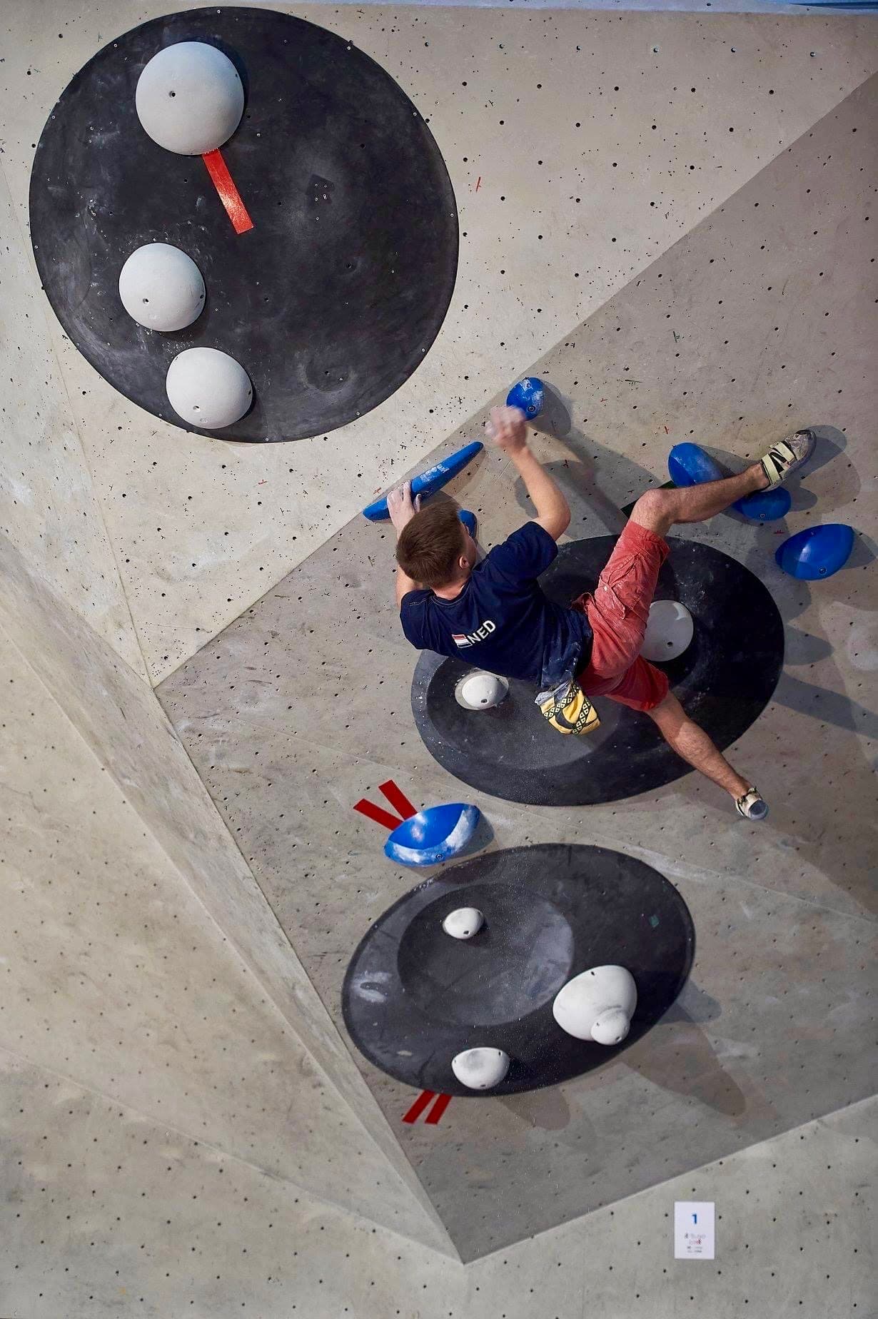Competing on a bouldering wall in a Netherlands jersey