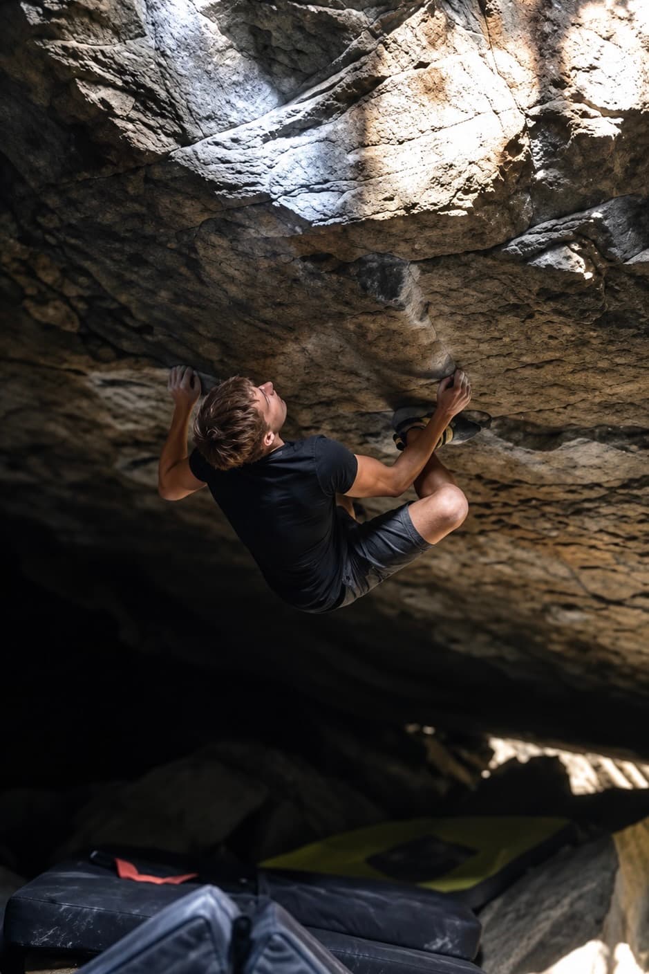 Cut loose under a steep granite roof in the shade at Magic Wood, crash pads on the ground below
