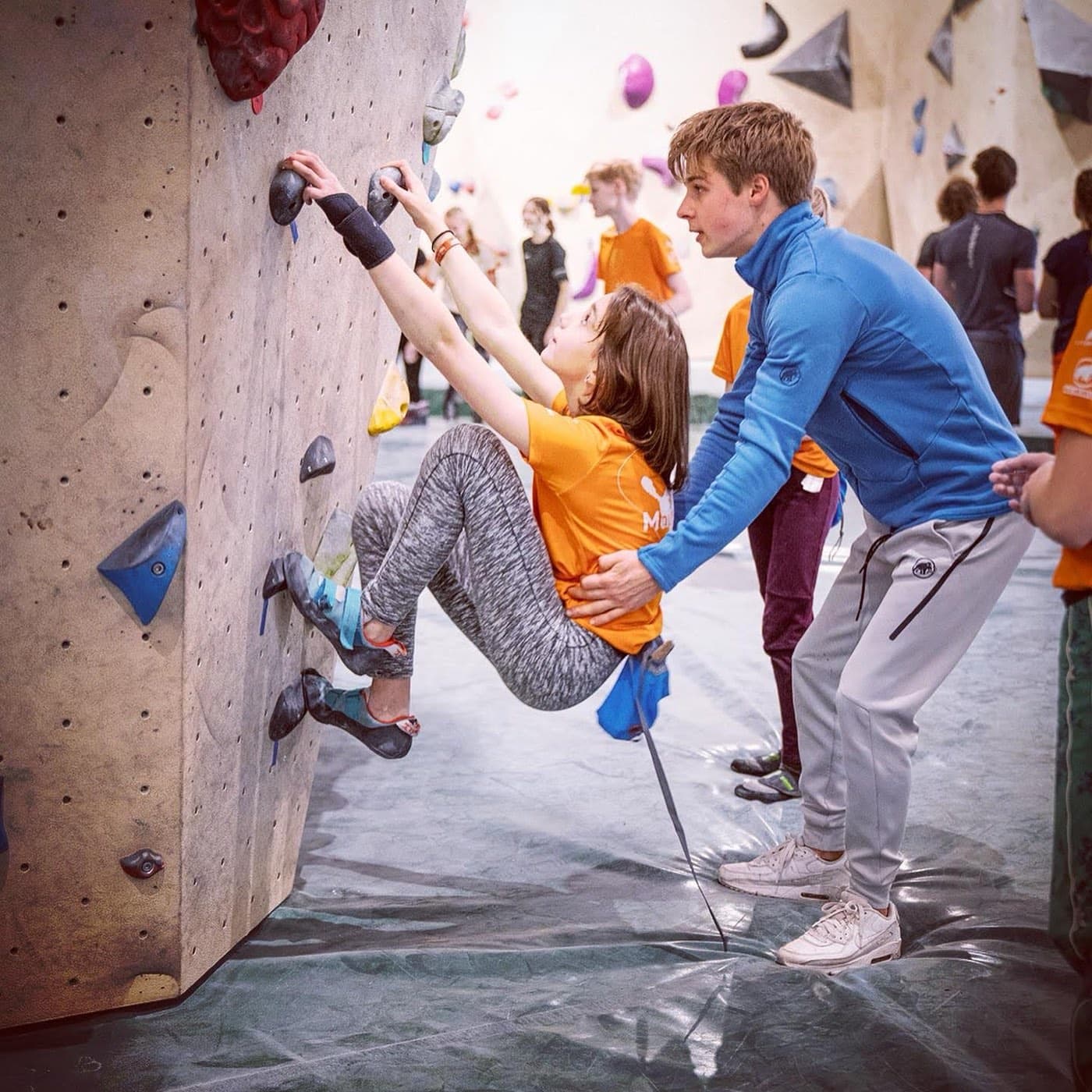 Giving hands-on climbing instruction to a young climber on an indoor wall