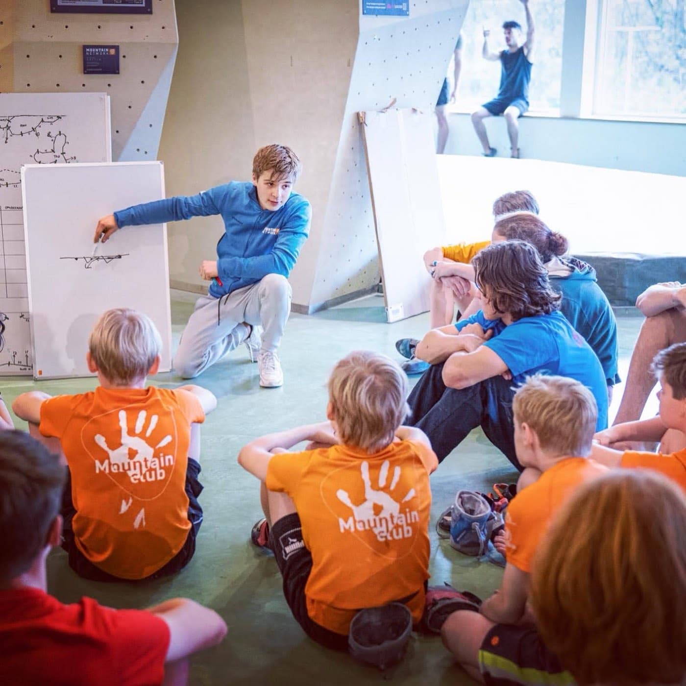 Explaining climbing movement to a seated group of youth climbers
