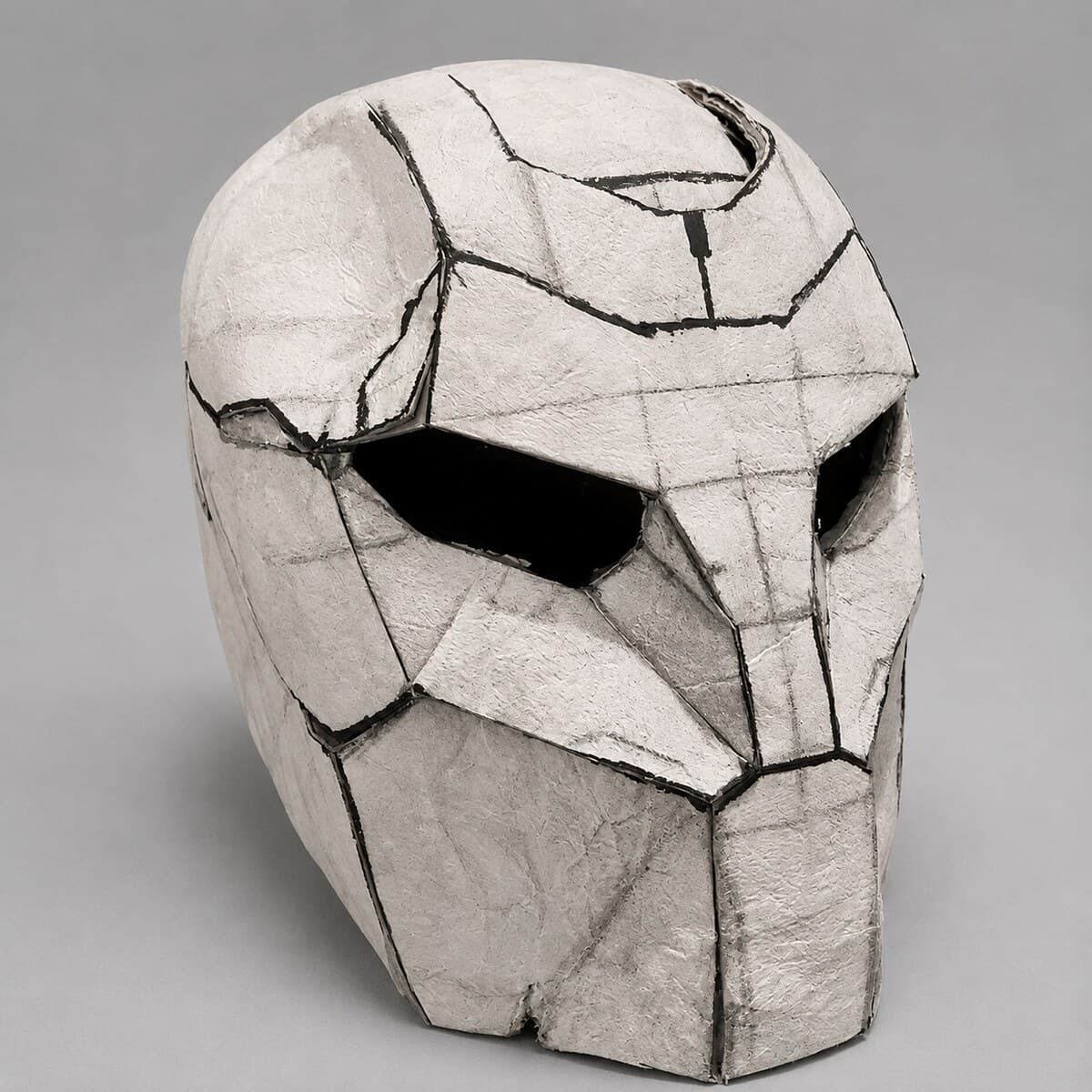 The helmet shell in a smooth pale surface, the facet lines still readable