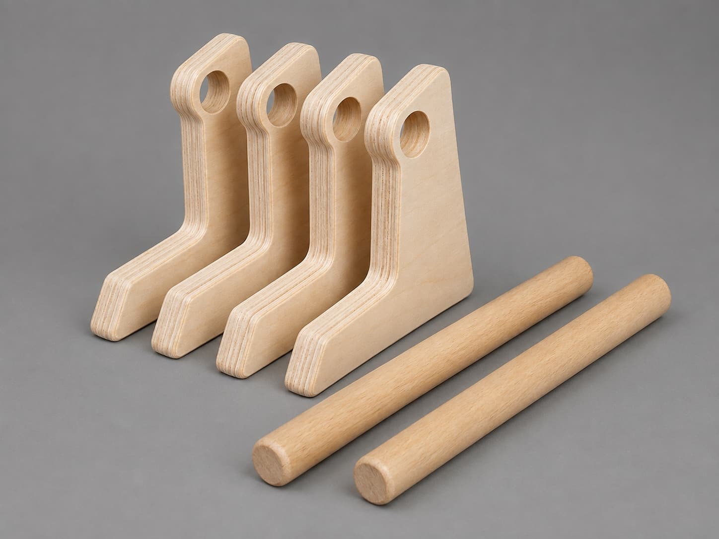 Four shaped birch plywood parallette ends beside two turned beech rails, before assembly