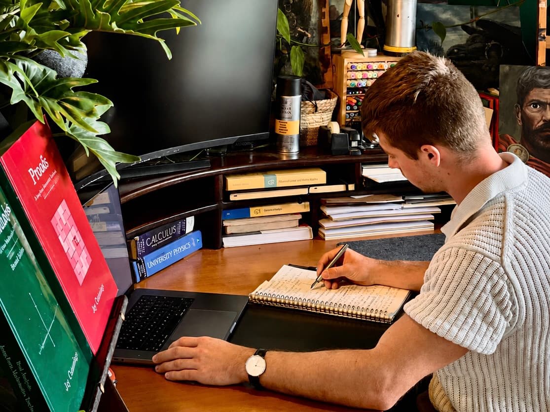 Leto schrijft collegeaantekeningen aan zijn bureau, naast een stapel wiskundeboeken